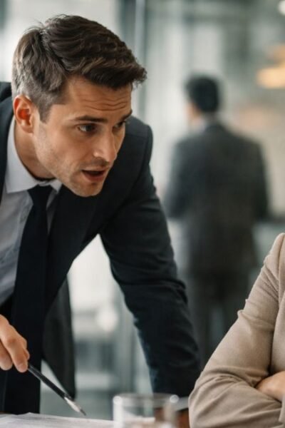 Cliente em postura retraída enquanto vendedor inclina o corpo de forma insistente em ambiente corporativo elegante simbolizando pressão comercial causada por experiência fraca