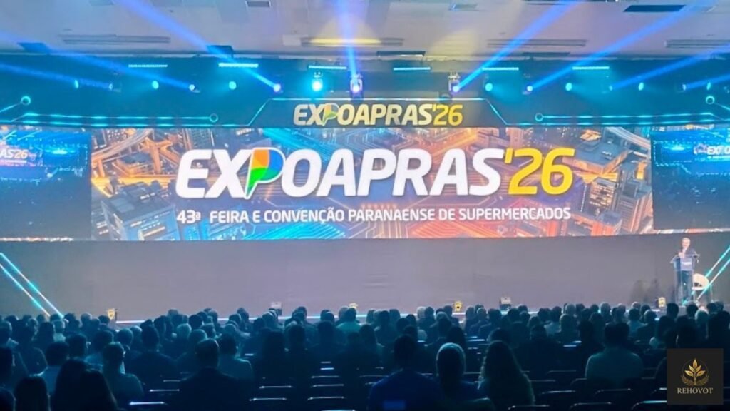 Auditório lotado durante evento empresarial com plateia atenta diante de palco iluminado e apresentação estratégica em telão