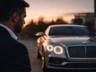Homem elegante observa carro de luxo ao entardecer com expressão reflexiva, não celebratória